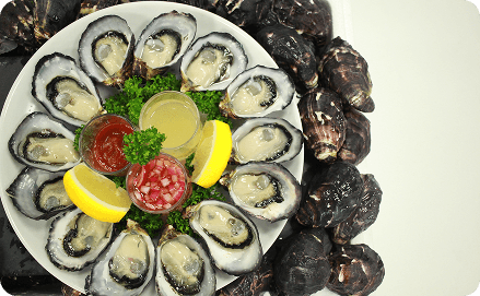 Oysters grilled with lemon wedges